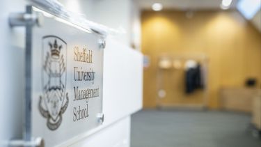 The podium in the Middleton Lecture displaying the Management School's logo.