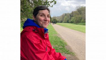 Julia sat in the countryside in a red walking coat