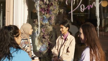 Four students sat drinking coffee outside Pom Kitchen