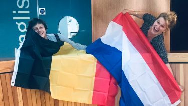 Two tutors with a Belgian and a dutch flag jokingly