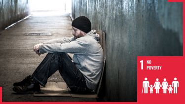 homeless man sat in underpass with sdg1 logo overlaid