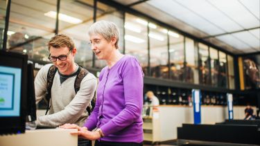 A student speaking to a member of staff as Western Bank Library.