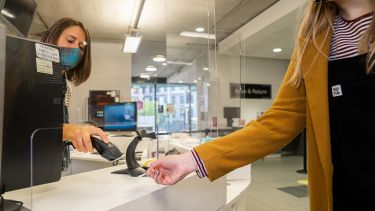 A student having their UCard scanned by a member of library staff