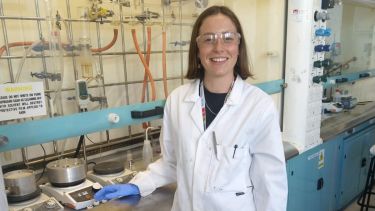 PhD student Amelia Wood in a laboratory by a fume cupboard.