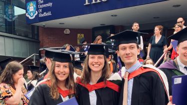 Three students in gowns smiling 