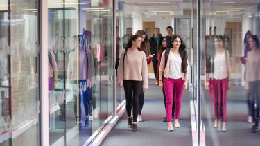 Students walking down the Management School's glass walkway.