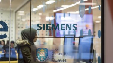 A student sat behind a window with the Siemens logo