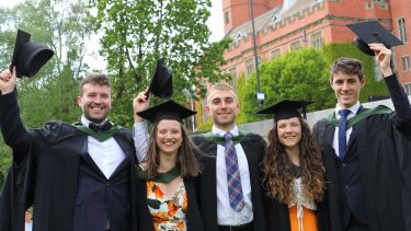 Graduates outside with caps off