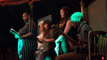 Festival of the Mind in the Spiegeltent, a multiple people read from a book as a person plays guitar
