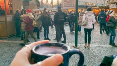 Image of cup of hot chocolate in front of German Christmas market