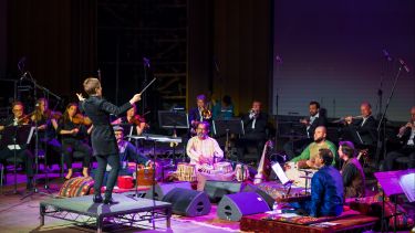 Dr Ponchione-Bailey conducting a large band of musicians on stage