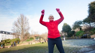 Older woman exercising in cold weather wearing a red jacket and gloves