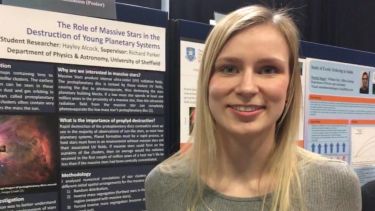 Undergraduate student Hayley Alcock presents her research at a poster symposium.