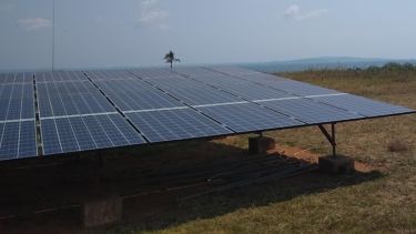 a large set of solar panel sits on dry arid grassland in tanzania. The are quite high above the ground. 