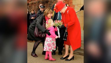 Her Majesty receives flowers from a child, who's accompanied by their mother.