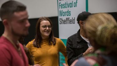 A woman smiling looking at a busy crowd during a previous Off The Shelf festival