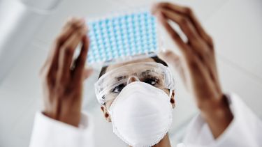 Technician in face mask with tray of samples