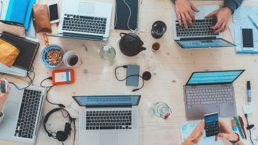 Table of laptops, phones, tea and coffee