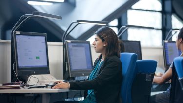 A girl sits in front of a desktop computer