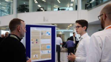 Photograph of delegates at the 2022 EPSRC Future Electrical Machines Manufacturing Hub conference presenting posters detailing their work