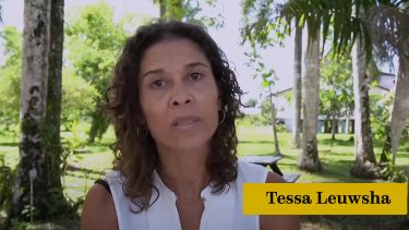 Surinamese Dutch author Tessa Leuwsha looking straight at the camera with tropical tress in the background