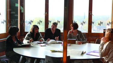 Students sit around a table in a seminar room