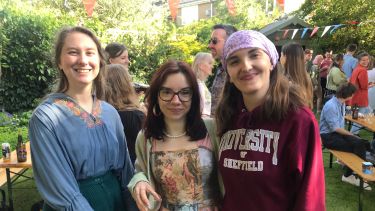 three young women smiling at the camera during an outdoor party