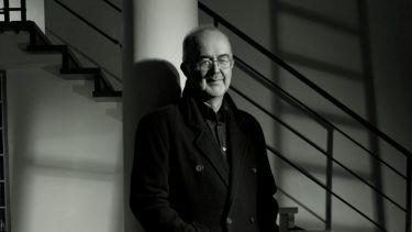 Man standing against pillar looking at camera - black and white image