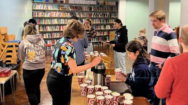 A group of people queue for coffee and food as it is handed out by volunteers.