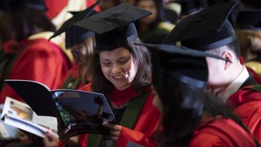 Postgraduates in Octagon Hall reading a programme