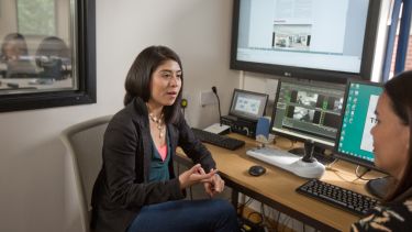 PhD student in the Information School discussing something at a computer