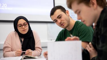 Three Oncology students discussing something and looking at notes