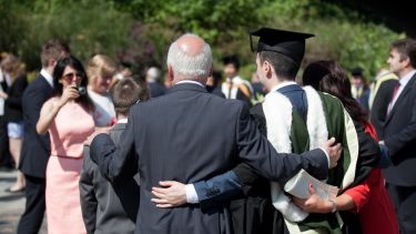 Graduate with arm round guest having photo taken