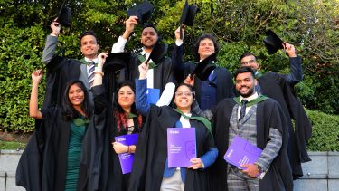 Students holding hats in air with happy faces