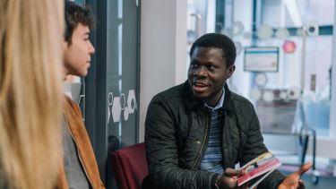 An academic talking to two students.