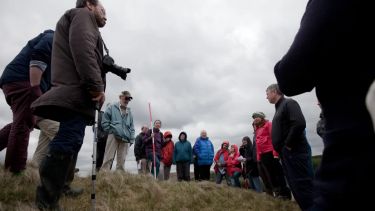 A large group meeting outdoors for a festival with some cloudy weather. The shot is taken from low down.