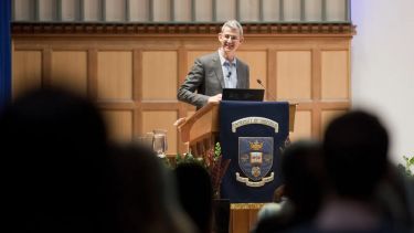 An individual on a formal stage, giving some kind of speech to an audience