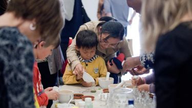 A group of younger individuals creating art of some kind, with adult supervision and assistance