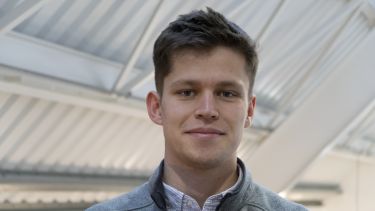 Tobias Darroach wearing a white shirt and a grey jumper.