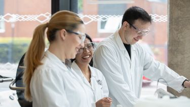 Three people in lab coats smiling in the Pilot Plant