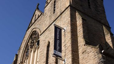 Part of a traditional building with a banner reading Drama Studio