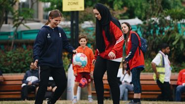 Two girls playing football in the Peace Gardens, Sheffield.