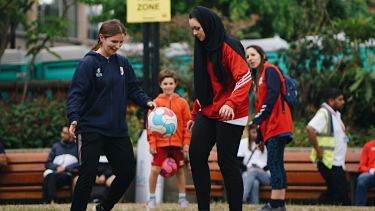 Two girls playing football in the Peace Gardens, Sheffield.