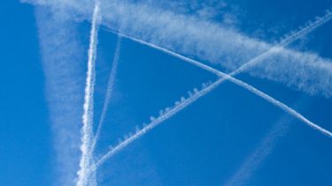 trails from planes criss-cross over a blue sky