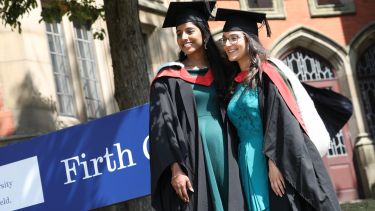 Graduates stood on firth court flower bed