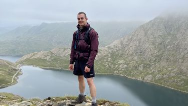 Bradley stood in a mountainous area in front of a river or lake
