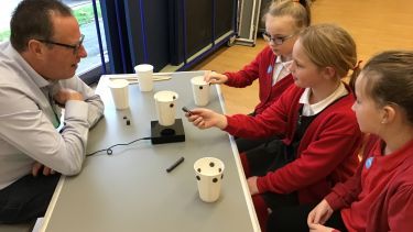 School children conducting an experiment in engineering overseen by an engineer