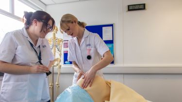 Two student midwives using a pregnancy simulation tool