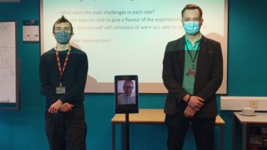 Two men stood by an iPad