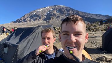 Band brothers brushing their teeth in front of Mount Kilimanjaro 